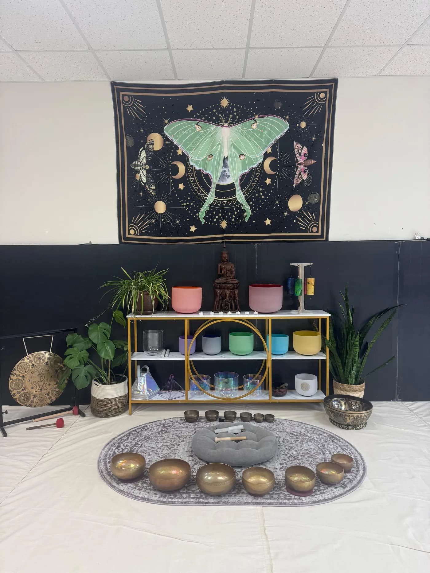 Crystal singing bowls and brass bowls beneath the luna moth tapestry